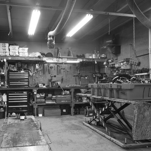 A black and white photo of different bike parts and tools hanging on the wall of the garage